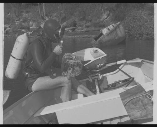 Shot of scubadiver sitting on edge of boat holding underwater camera equipment at sea