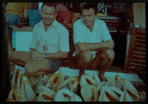 Shot of two people sitting with a collection of Conch shells