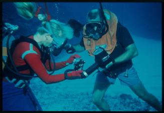 Underwater shot at the sea floor of Valerie Taylor scuba diving holding an underwater camera set up with a second scuba diver