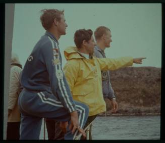 Shot of three people looking and pointing out to sea standing on wharf