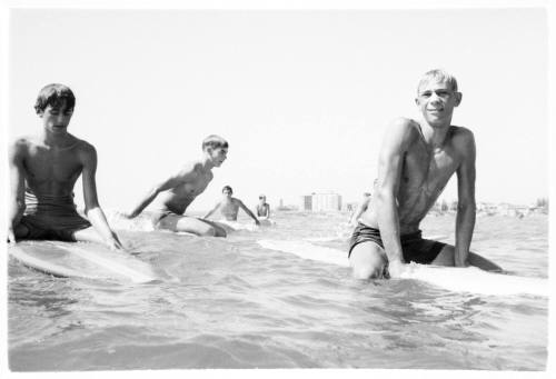 Black and white shot at water surface of group sitting out at sea on surfboards