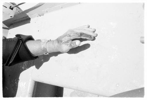 Black and white shot of a diver's exposed hand and wrist out of wetsuit resting on table