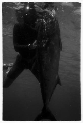 Black and white underwater shot of freediver holding caught fish