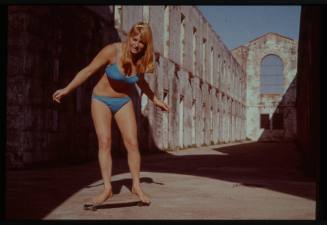 Shot of person skateboarding in swimwear on a concrete site