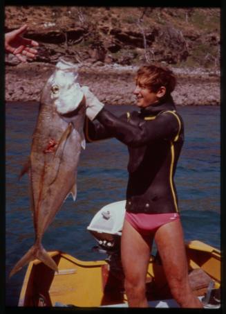 Shot of person holding up caught fish on board a boat