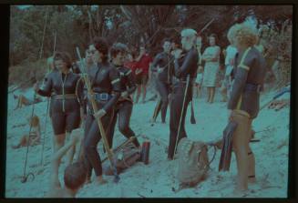 Shot of group of people in freediving gear and holding equipment like spear rods on a beach