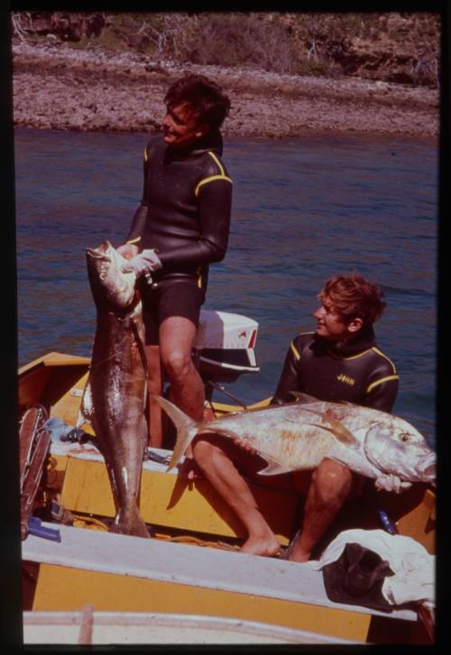 Shot of two people holding caught fish on board a boat at sea