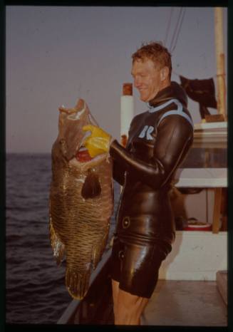 Shot of person holding caught fish on board boat at sea