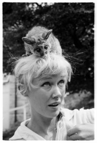 Black and white close up portrait of Valerie Taylor with possum on her head