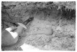 Black and white shot of hand holding a knife with a rocky floor in background