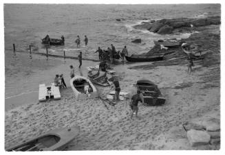 Black and white long shot of beach shore with group of people and group of dinghies ashore