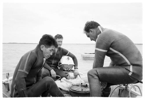 Black and white topside shot of three divers on a dinghy at sea