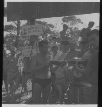 Shot of person holding a caught fish near scale amongst a crowd at a weigh in area