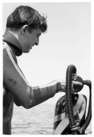 Black and white medium shot of Peter Harper topside holding air tank
