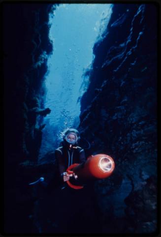 Valerie Taylor swimming through an underwater crevice