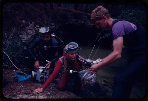 Valerie and Ron Taylor climbing out of water aided by a third person