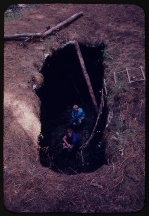 Hole in ground with two people inside