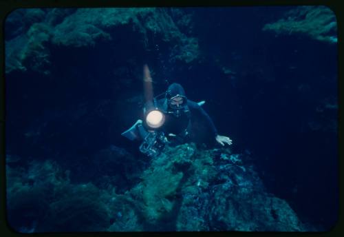 Ron Taylor underwater with torch and camera