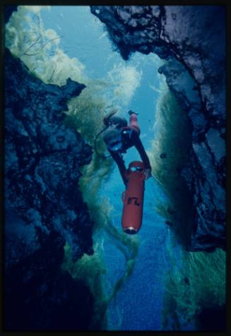 Valerie Taylor swimming down an underwater crevice