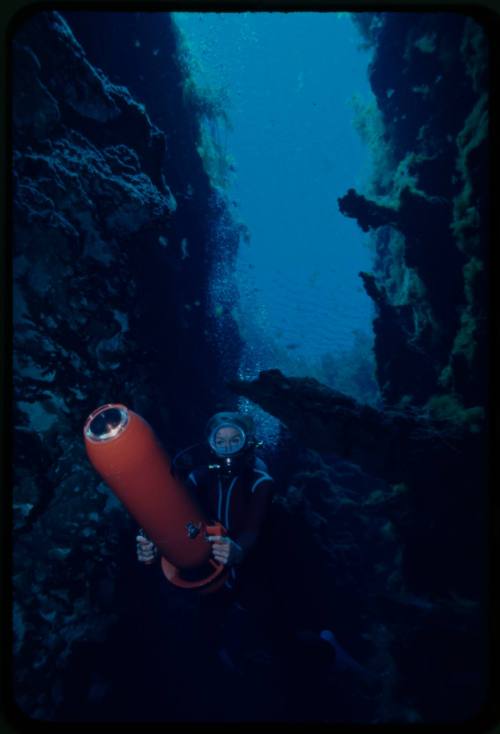 Valerie Taylor swimming through an underwater crevice