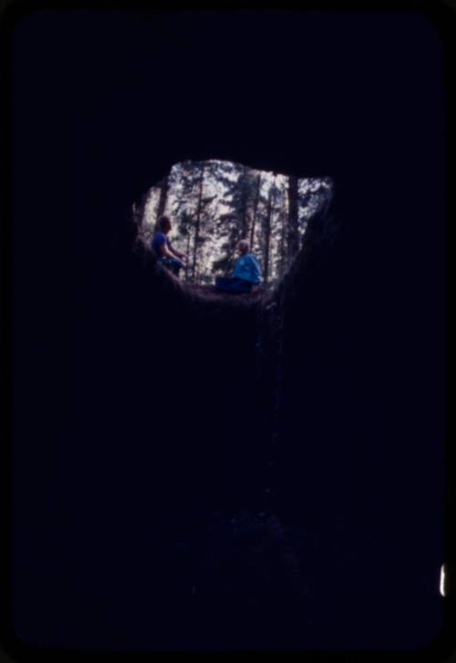 Two figures looking down into a hole in the ground