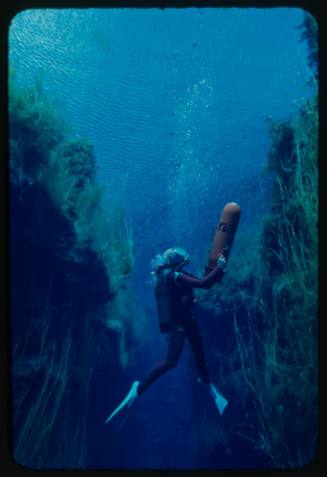 Valerie Taylor underwater with orange underwater scooter in hands