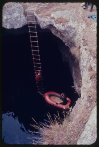 Red inflatable boat in a pool of water below ground