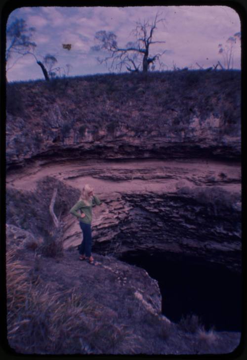 Valerie Taylor standing on edge of a sink hole