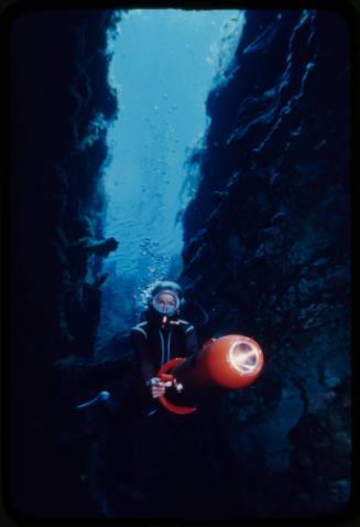 Valerie Taylor swimming through underwater crevice