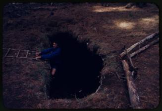 Ron Taylor on rope ladder at edge of hole in ground