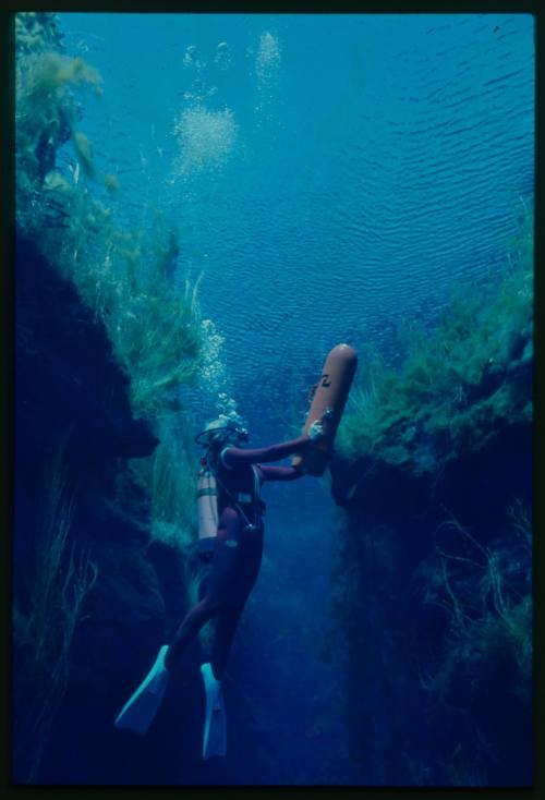 Valerie Taylor underwater swimming out of crevice