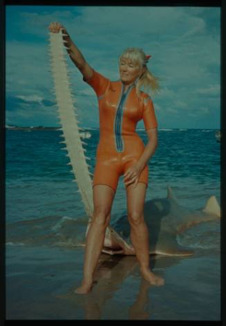 Valerie Taylor on beach holding nose of sawfish