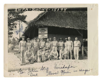 Group of men posing for photograph in front of hut