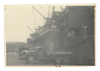 Trucks on dock next to large vessel