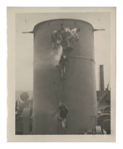 Three men in shorts on the funnel of HMS KANIMBLA