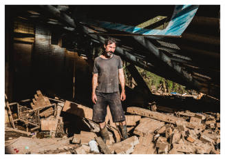 Man under a fallen roof amongst bricks