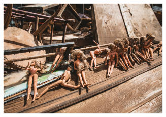 Line of Barbie dolls on wooden debris