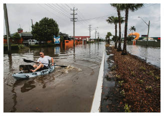 Man and dog in kayak on a flooded road