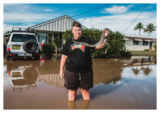 Person holding a snake on flooded street