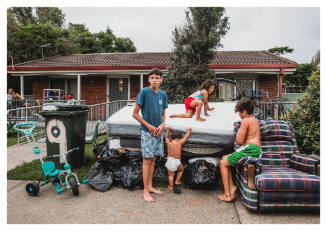 Four children amongst pile of thrown out household items