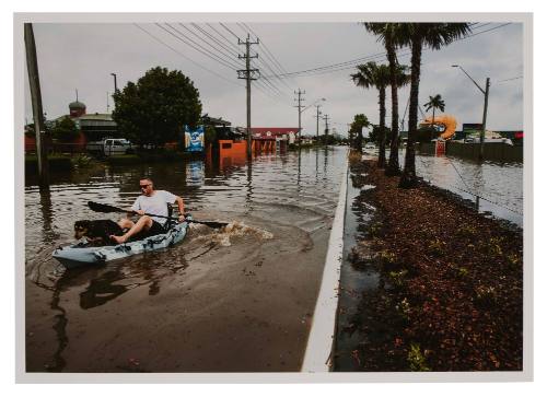 Man and dog in kayak on a flooded road