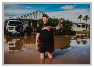 Person holding a snake on flooded street