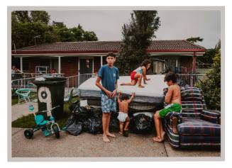 Four children amongst pile of thrown out household items