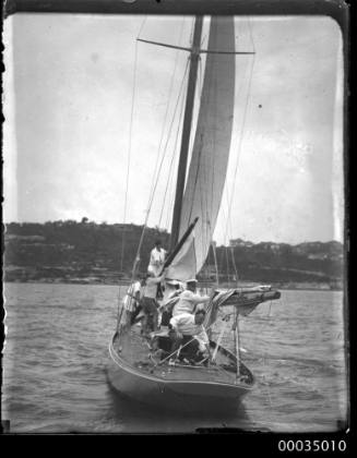 Crew attending to sails on deck of sailing boat