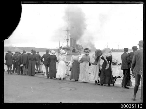 Spectators watching a naval vessel in the harbour, possibly the Japanese cruiser HIJMS IZUMO