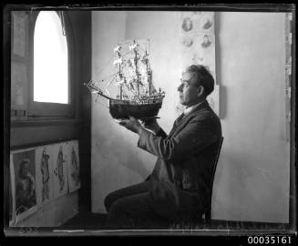 Man holding up a model of 16th century ship