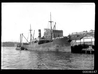 Cargo ship alongside wharf with  Erich & Co Ltd, Wolfes Schnapps, Nicholson & Co Bulk Store and Beech-Nut Chewing Gum sign