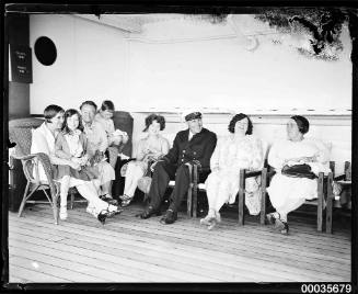 Ship's officer, passengers and children seated on the deck of SS ORUNGAL