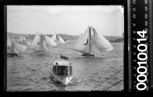 Mixed fleet of 18-footers, half-deckers and others and a ferry, Sydney Harbour