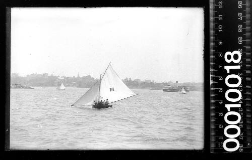 10-footer TRUANT displaying the number '33' on the mainsail and a steam ferry on Sydney Harbour